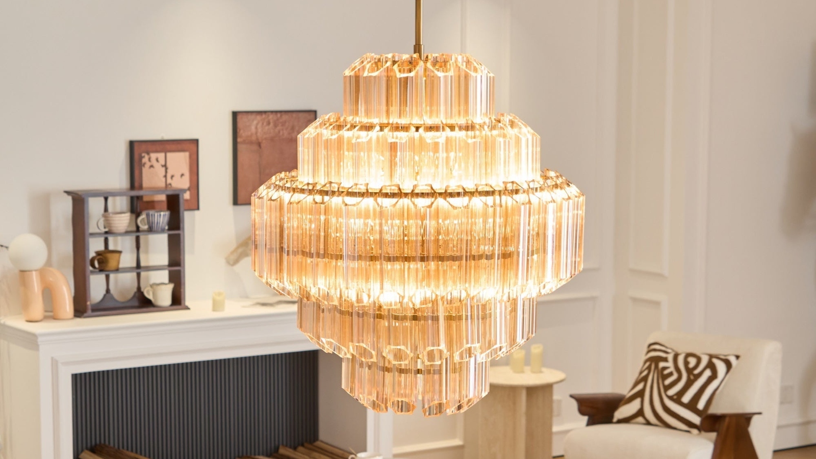 JINSHE Aurum Cascade Glass Chandelier suspended in high-ceiling modern living room with fireplace and plaster details